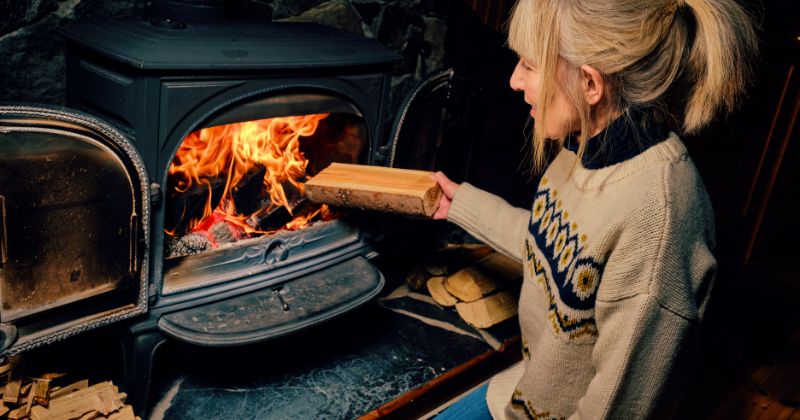 Woman burning wood for home heating alternatives.