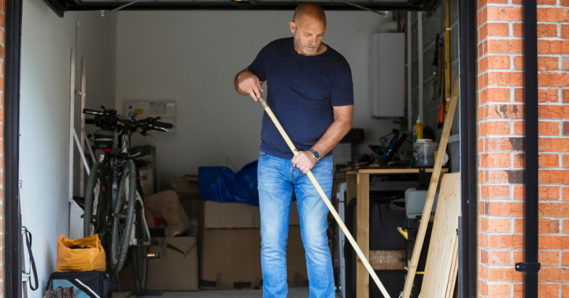 Man cleaning his garage in preparation for the installation of an electric garage radiator for the winter season.