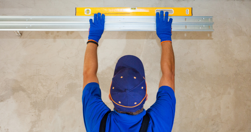 A worker checking the position for the installation of an electric garage radiator.