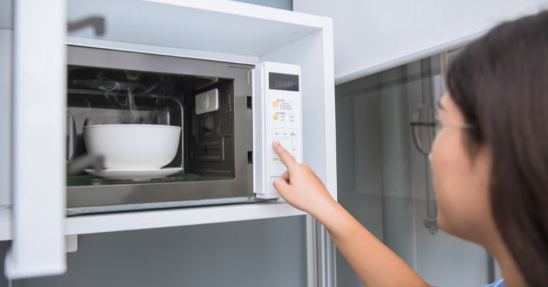 A woman utilising an energy-efficient microwave for her meals