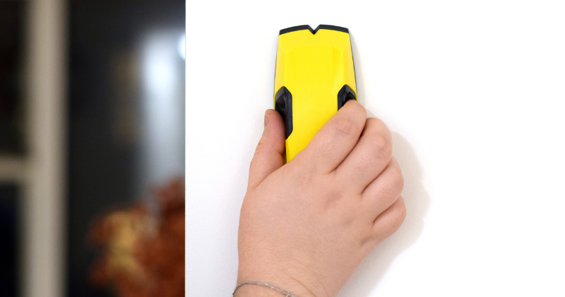 woman using a wall stud detector to locate live wire