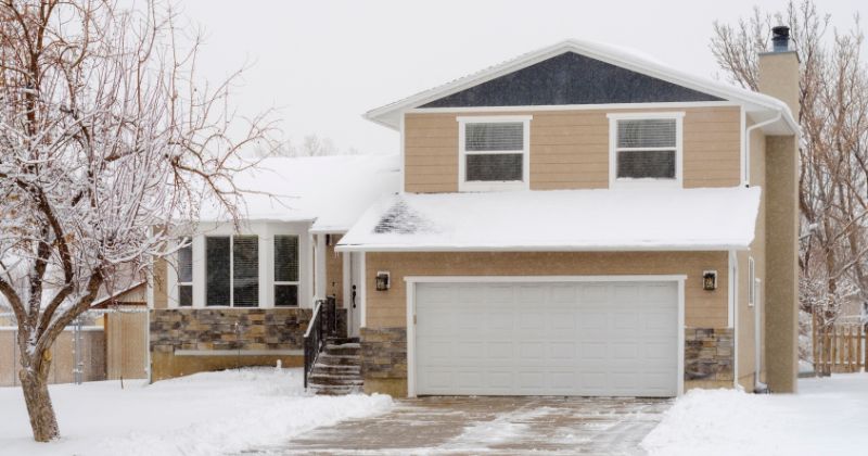 Beige-painted house surrounded by snow because it is winter.