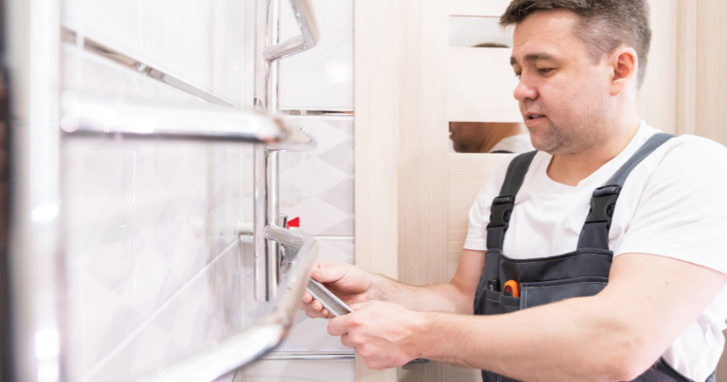 A man installing the heated towel rail for the luxurious touch of the bathroom.