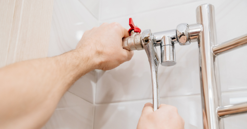 A man fixing, checking, and attaching pipe lines for the heated towel rack