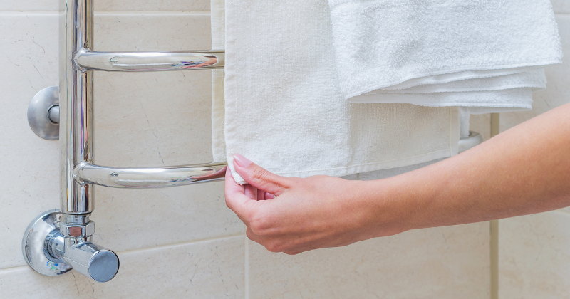 A white towel drying on a white radiator rail