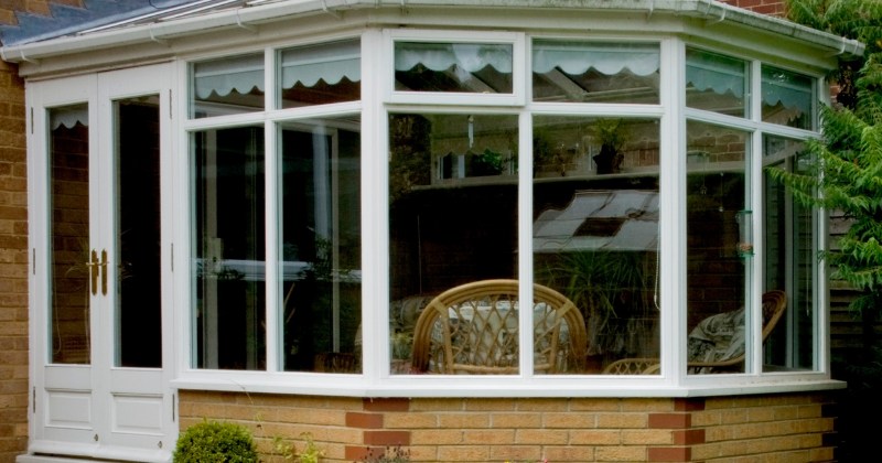 Spacious conservatory room with large white casement windows.