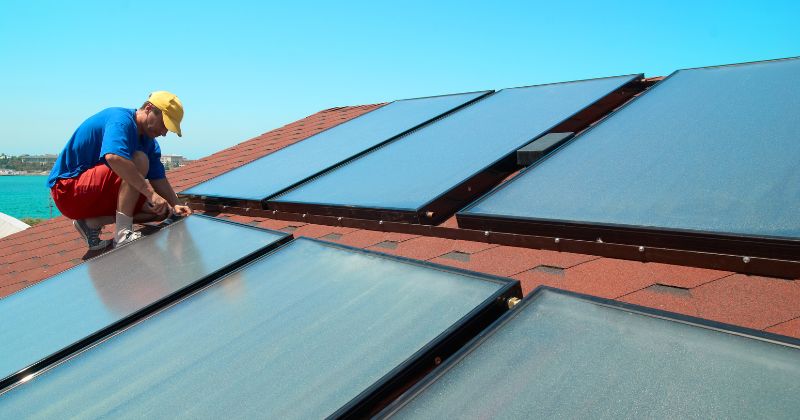 Man installing solar-powered electric heating on a rooftop