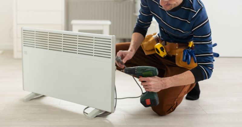 Man installing an electric panel heater in the living room.