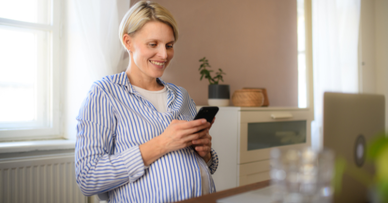 Pregnant woman browsing on phone, researching modern electric radiators