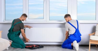 Two professionals fitting electric radiator onto white house.